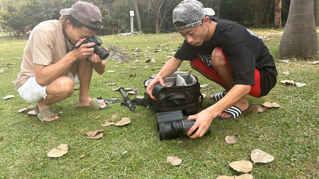 Learners handling camera lenses and photography equipment